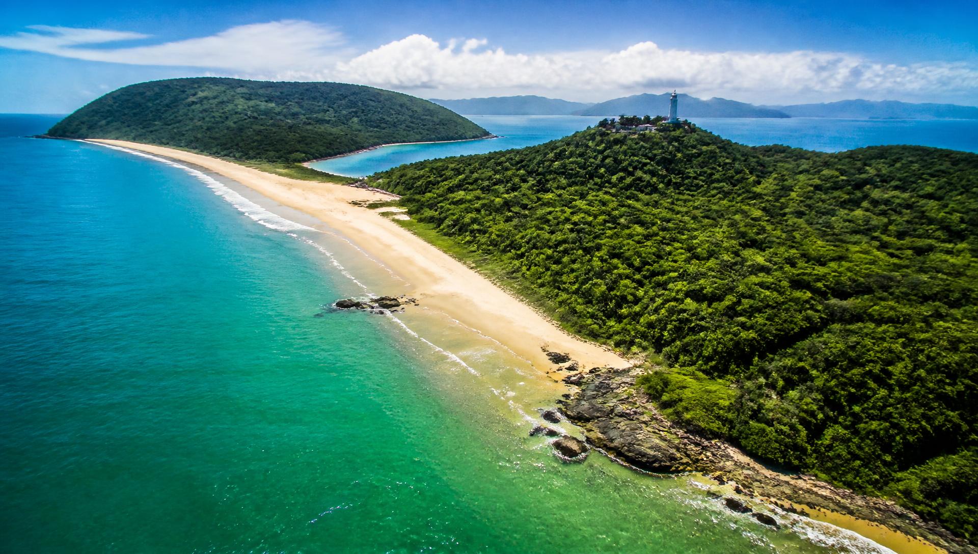 Vista aérea da Ilha do Mel com praia de areia clara, mata atlântica e o farol ao fundo